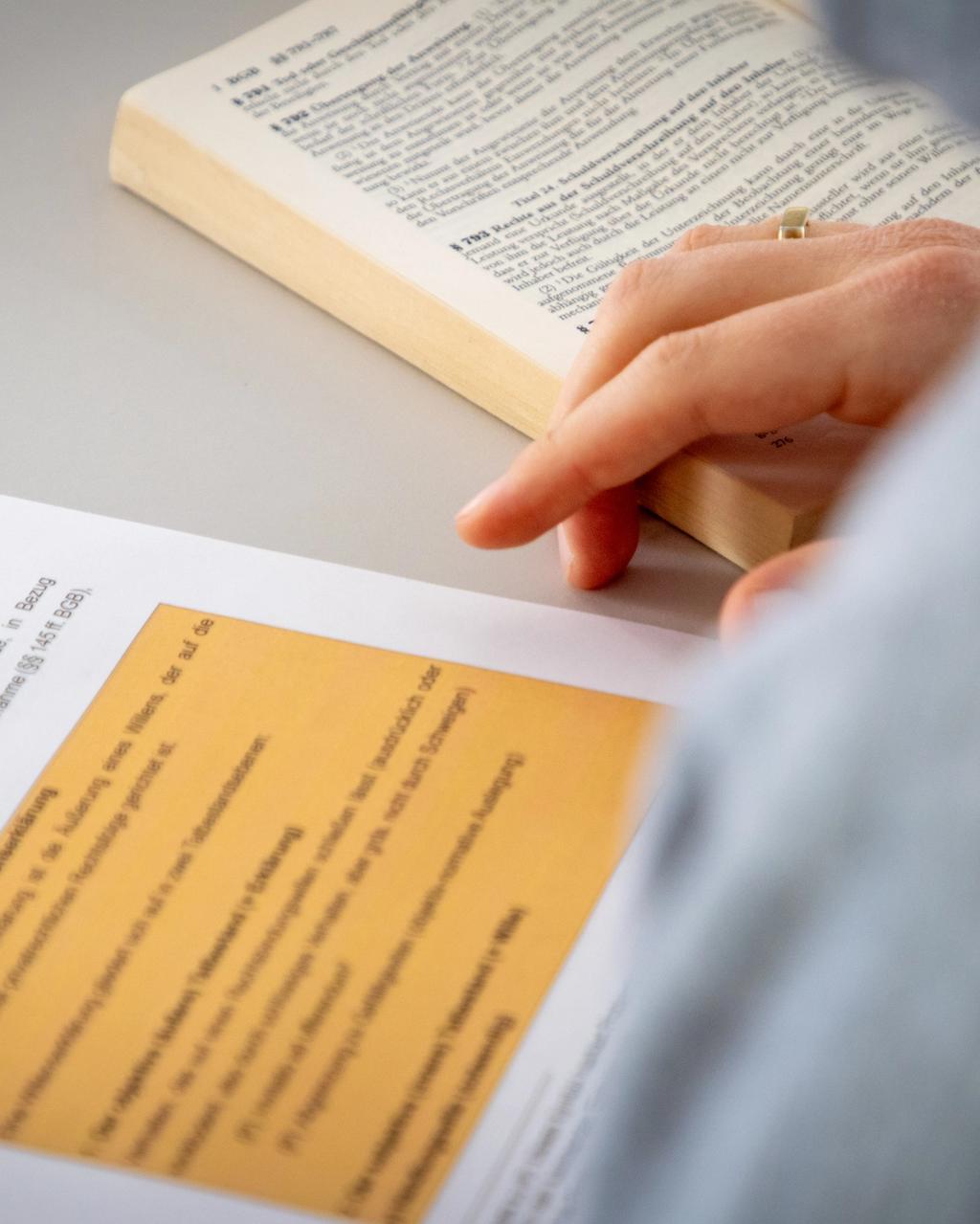 Jura-Student sitzt mit aufgeschlagenem Jura-Lehrbuch vor einer Jurakompakt-Übungsklausur