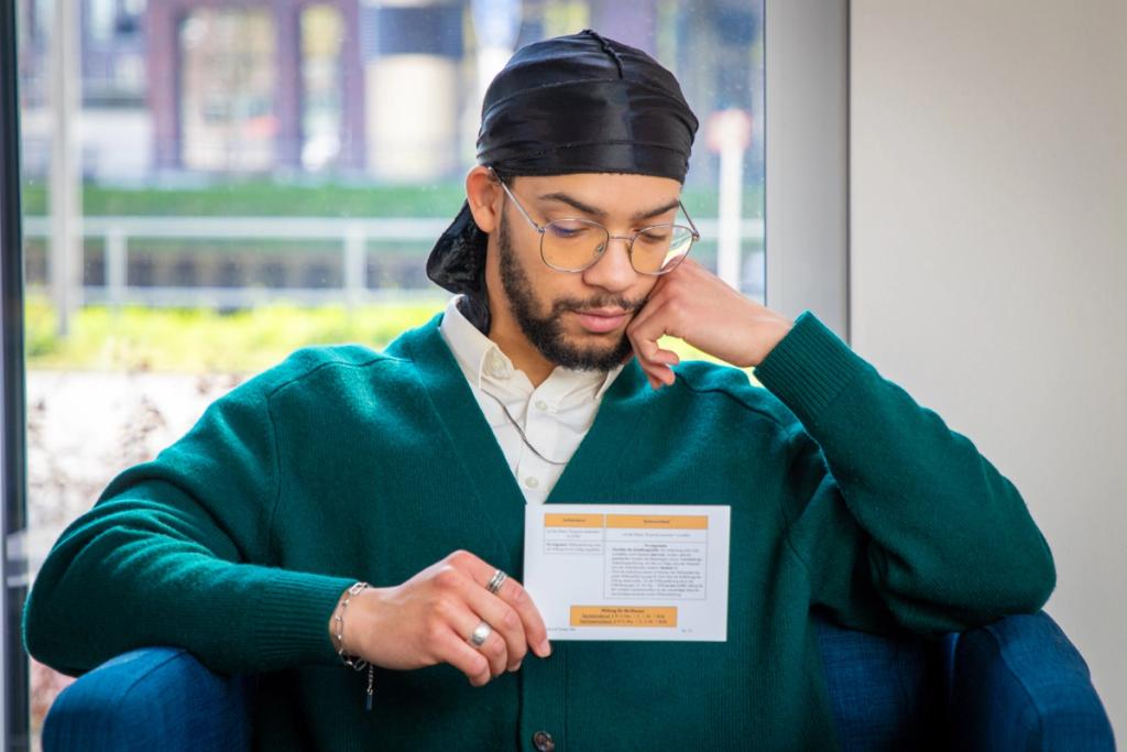 Student mit Brille lernt konzentriert mit Jurakompakt-Karteikarten vor Fenster mit Stadtblick