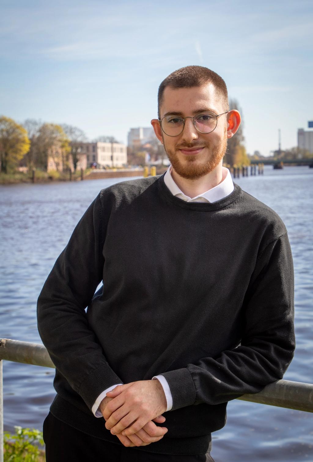 Lino, Jurakompakt-Mitgründer und Dozent, Portrait an einem Fluss mit Brille und schwarzem Pullover