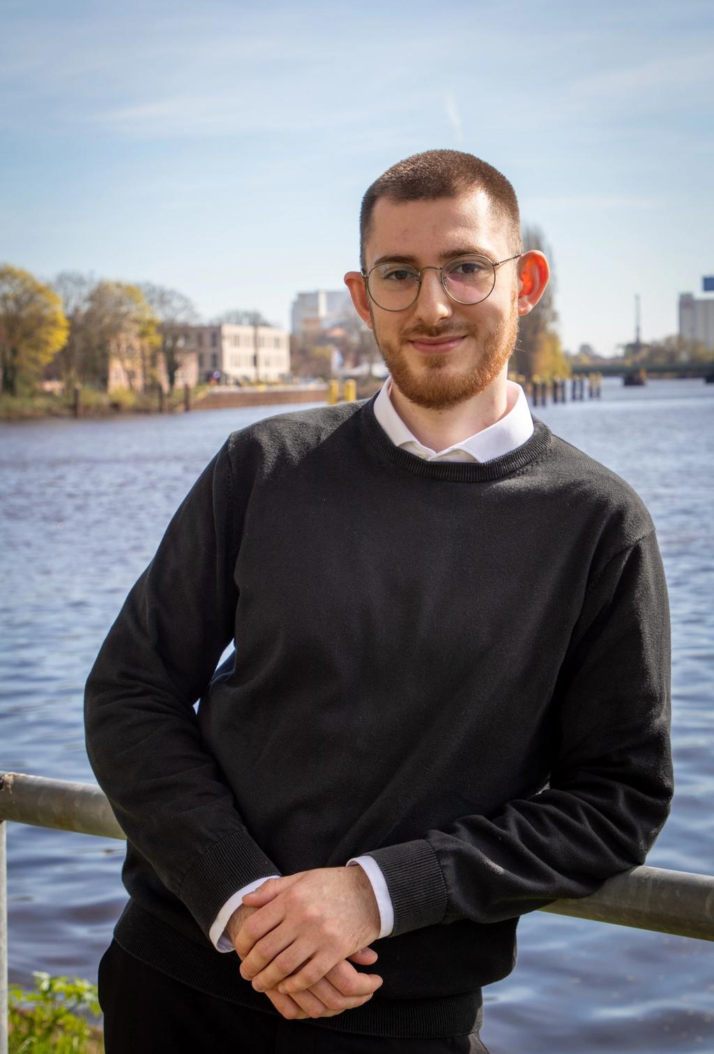 Lino, Jurakompakt-Mitgründer und Dozent, Portrait an einem Fluss mit Brille und schwarzem Pullover