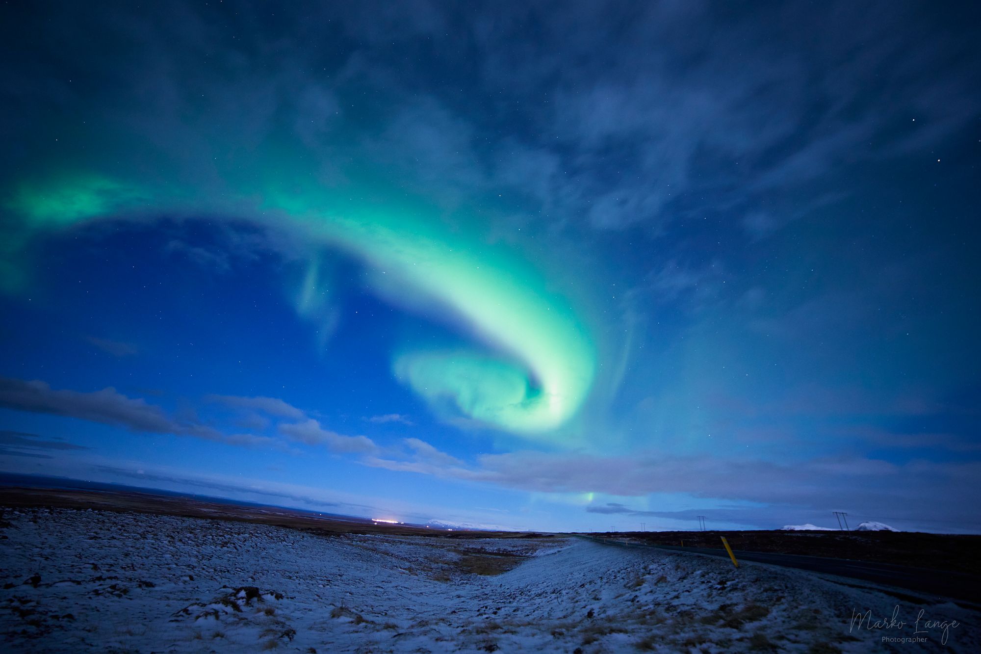 Grünes Nordlicht schwingt in weiten Bögen über dem dunklen Winterhimmel der Halbinsel Snæfellsnes.