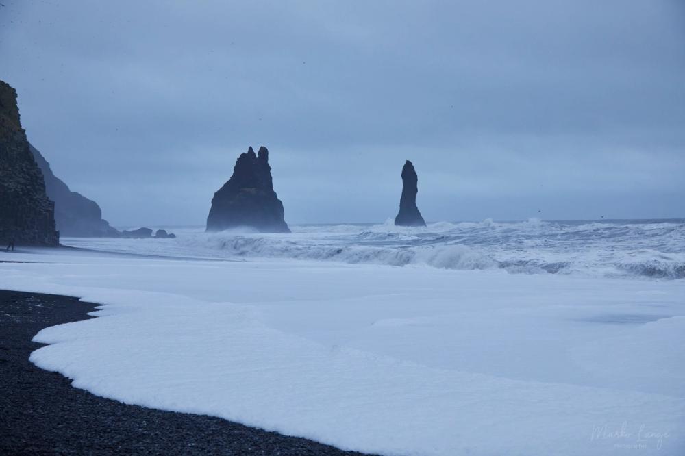 Mächtige Wellen brechen über dem schwarzen Vulkanstrand von Reynisfjara.