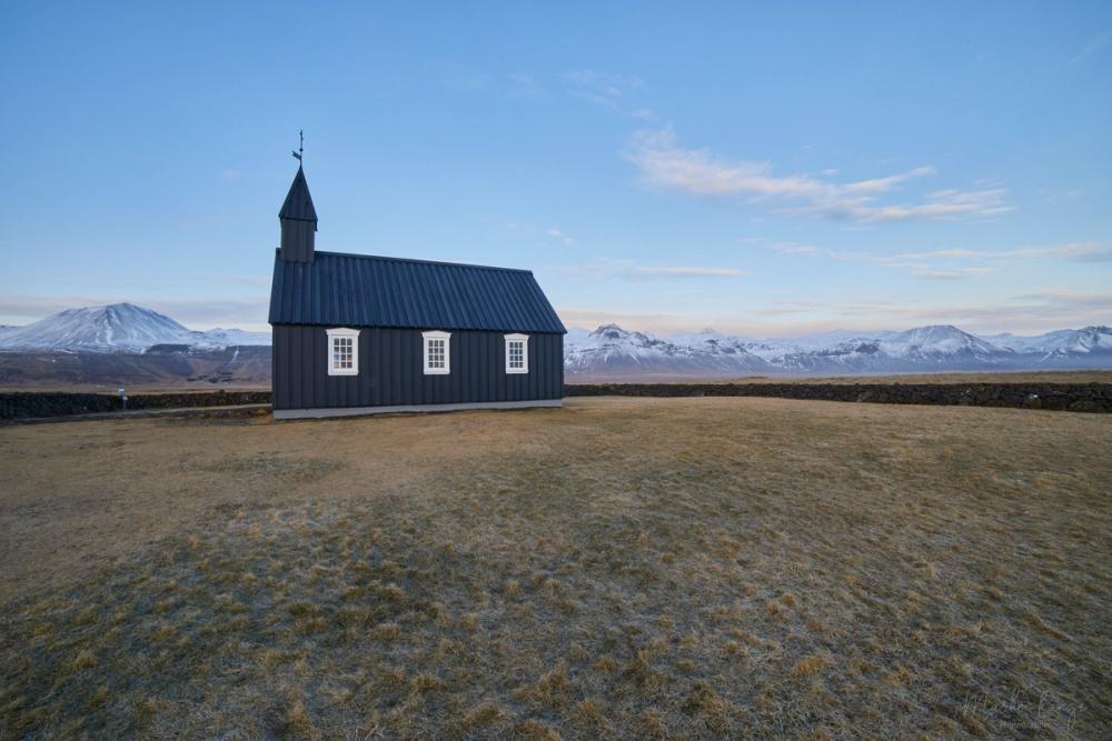 Ein niedriges Steinmäuerchen umgibt die einsame schwarze Kirche von Búðir.