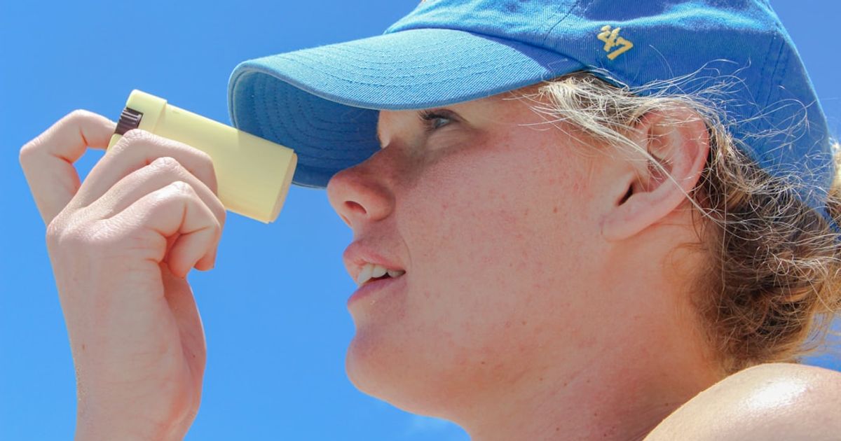 a woman wearing a blue hat looking through a magnifying glass