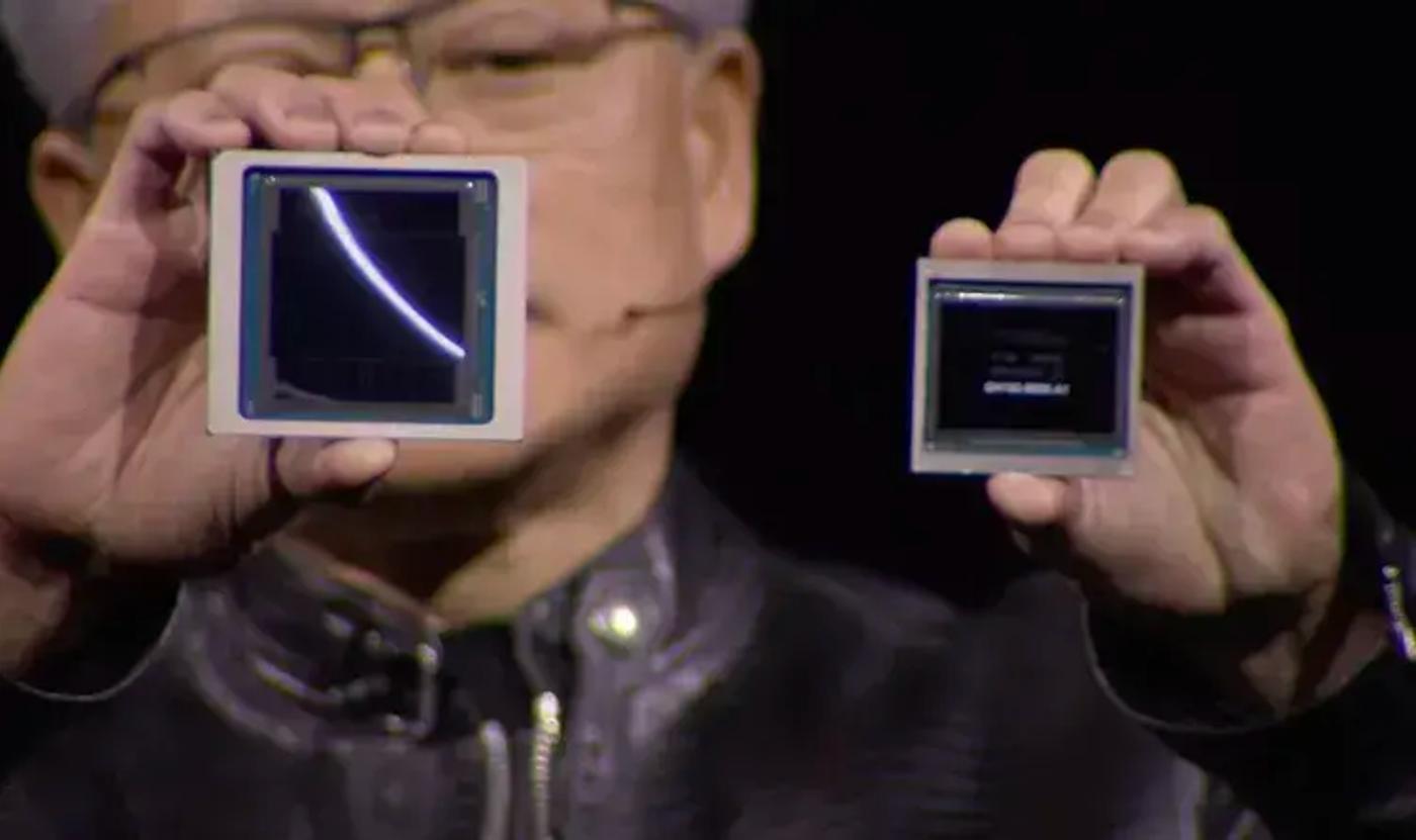 jensen huang holds up his new gpu on the left next to an h100 on the right