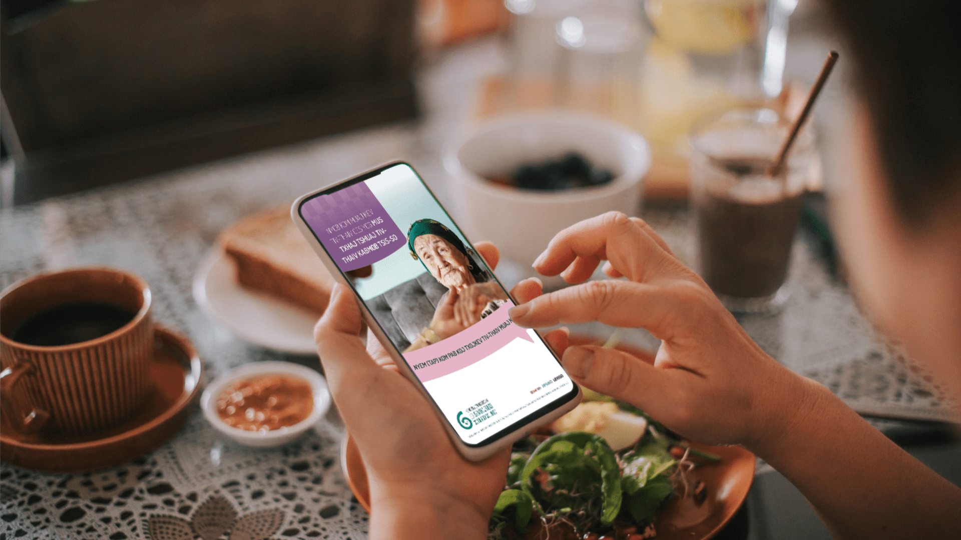Hands holding a phone over breakfast, showing an in-language health message with a photo of an older woman