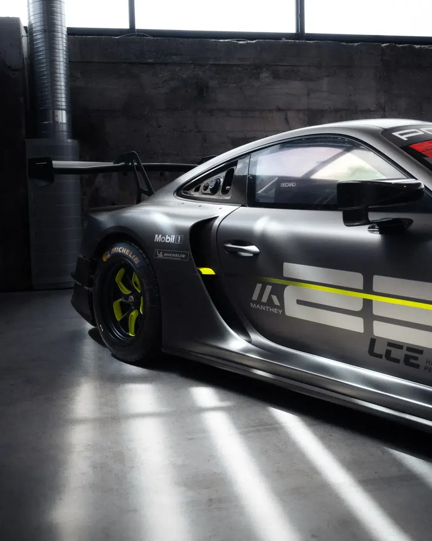 Seitenansicht des grauen Porsche GT3 R mit neongelben Akzenten auf dem MYLE 24