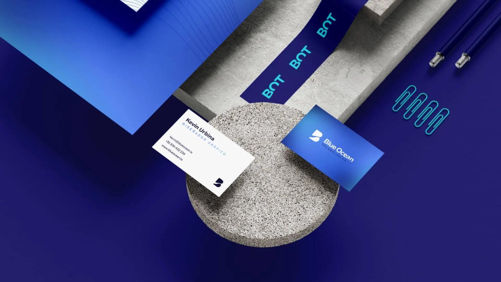Papelería corporativa de Blue Ocean Technologies mostrando tarjetas de presentación cintas y clips azules sobre bloques de concreto destacando la identidad visual y el logotipo de la empresa