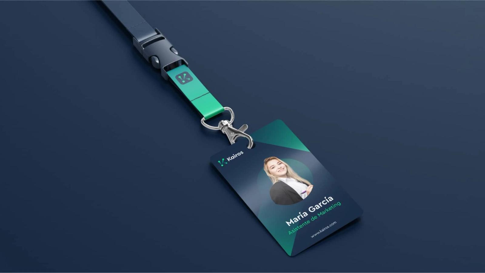 Tarjeta de identificación corporativa de Kairos con cinta colgante en tonos verde y azul mostrando fotografía de perfil cargo del empleado y logotipo de la marca sobre fondo oscuro
