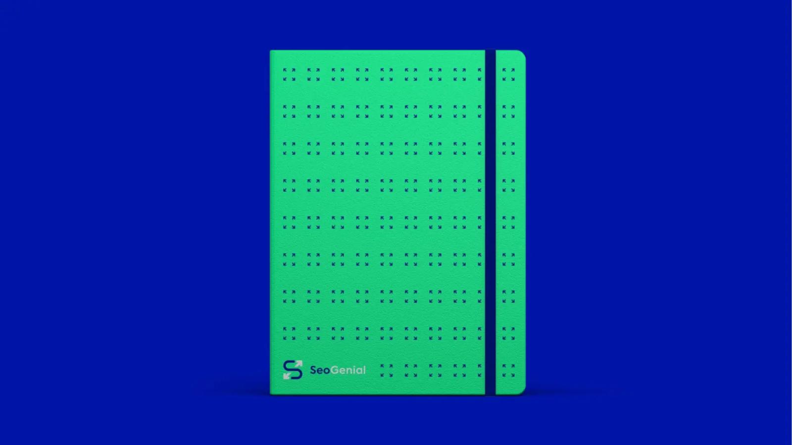 Libreta de color verde brillante con cierre elástico azul, decorada con un patrón de pequeñas flechas oscuras y el logotipo de 'SeoGenial' en la parte inferior, presentada sobre un fondo azul sólido