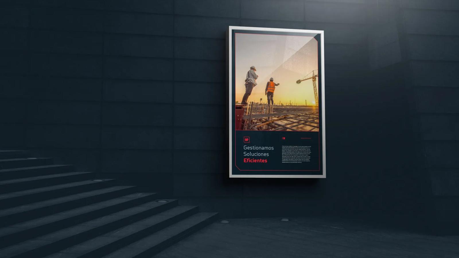 Panel publicitario iluminado en una pared exterior oscura junto a unas escaleras, mostrando una fotografía de trabajadores en una construcción al atardecer bajo el eslogan corporativo 'Gestionamos Soluciones Eficientes' en una base negra
