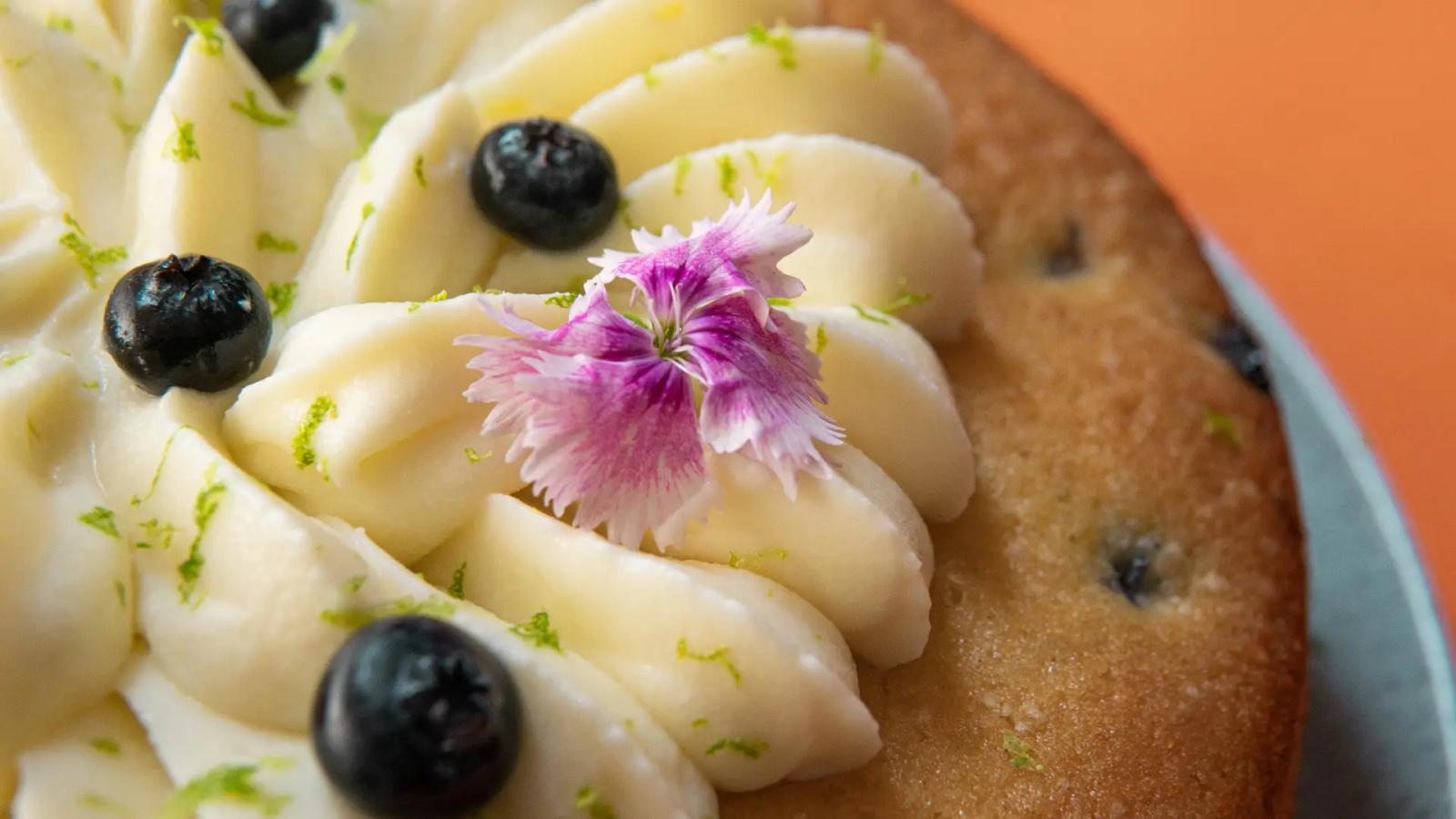 Torta casera decorada con crema frutas y flores comestibles