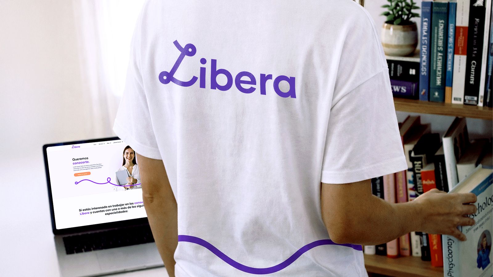 Camiseta blanca con logotipo de marca en entorno interior con laptop abierta