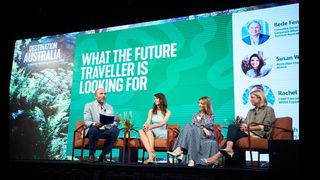 A group of speakers on stage in front of a large screen