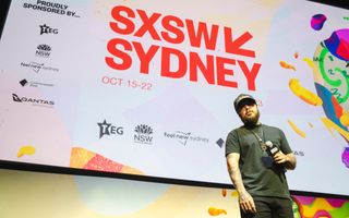 Post Malone standing on stage in front of a large screen with SXSW Sydney on display