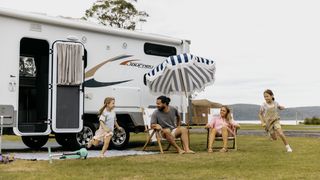 A family having fun in front of a caravan at Ocean Beach Holiday Resort in Umina.