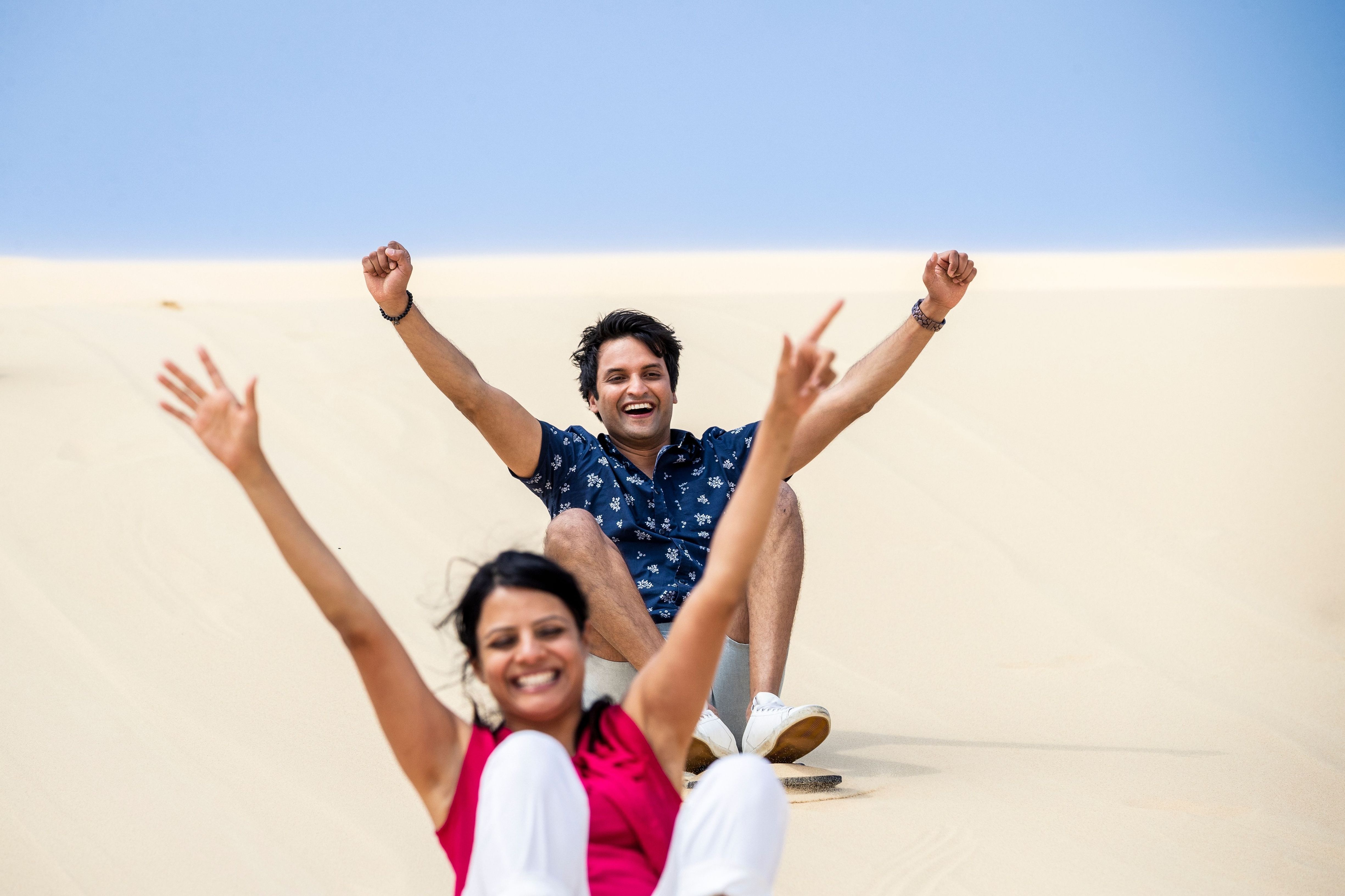 Couple enjoying sandboarding, Port Stephens.