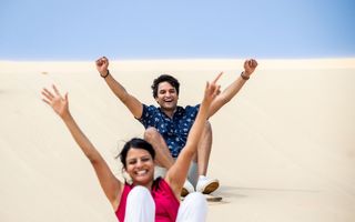 Couple enjoying sandboarding, Port Stephens.