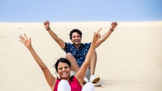 Couple enjoying sandboarding, Port Stephens.