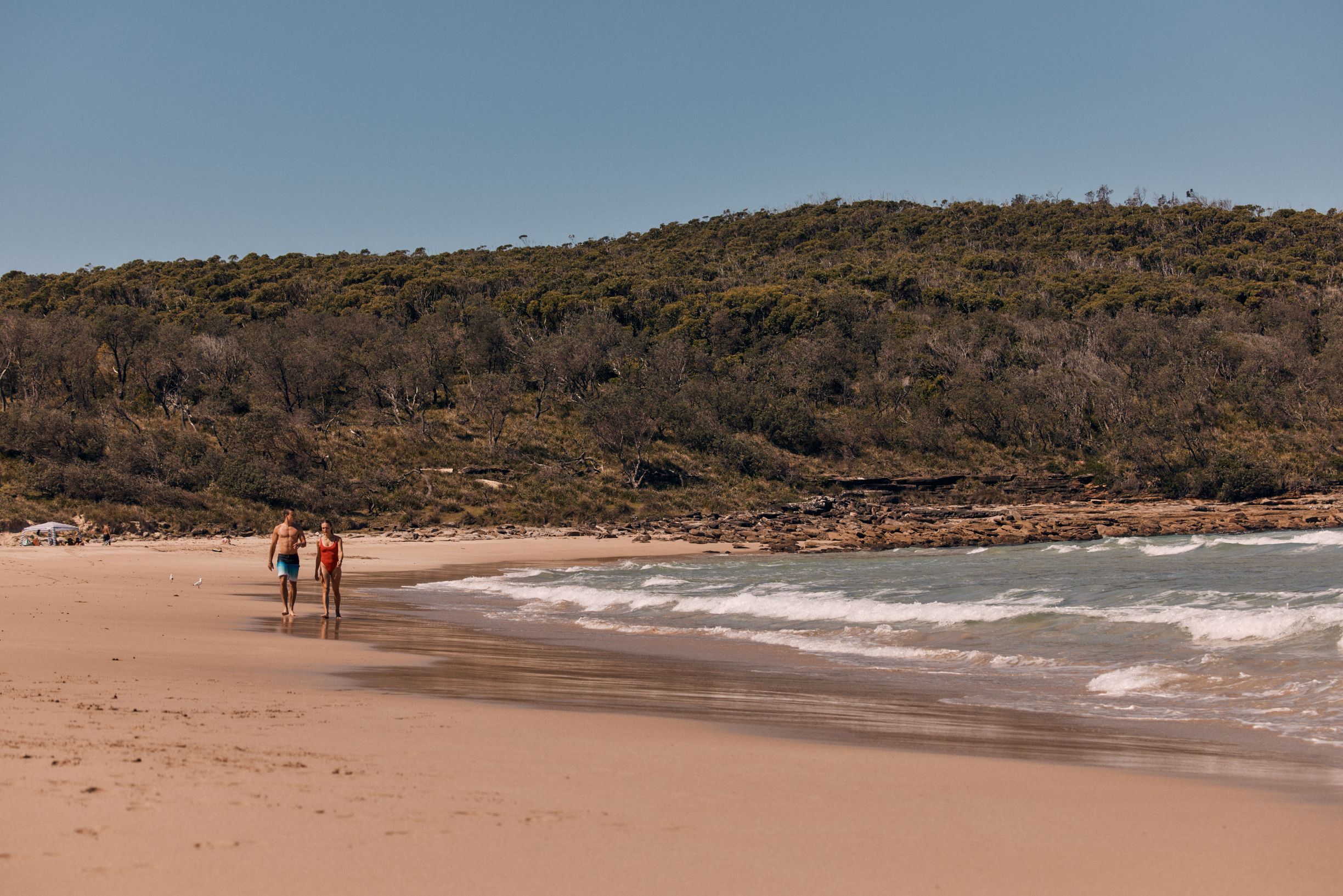 A couple enjoys the sand and sea at Pretty Beach