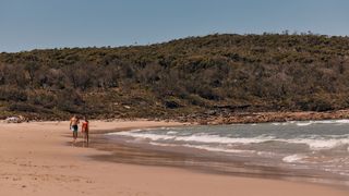 A couple enjoys the sand and sea at Pretty Beach