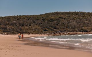 A couple enjoys the sand and sea at Pretty Beach