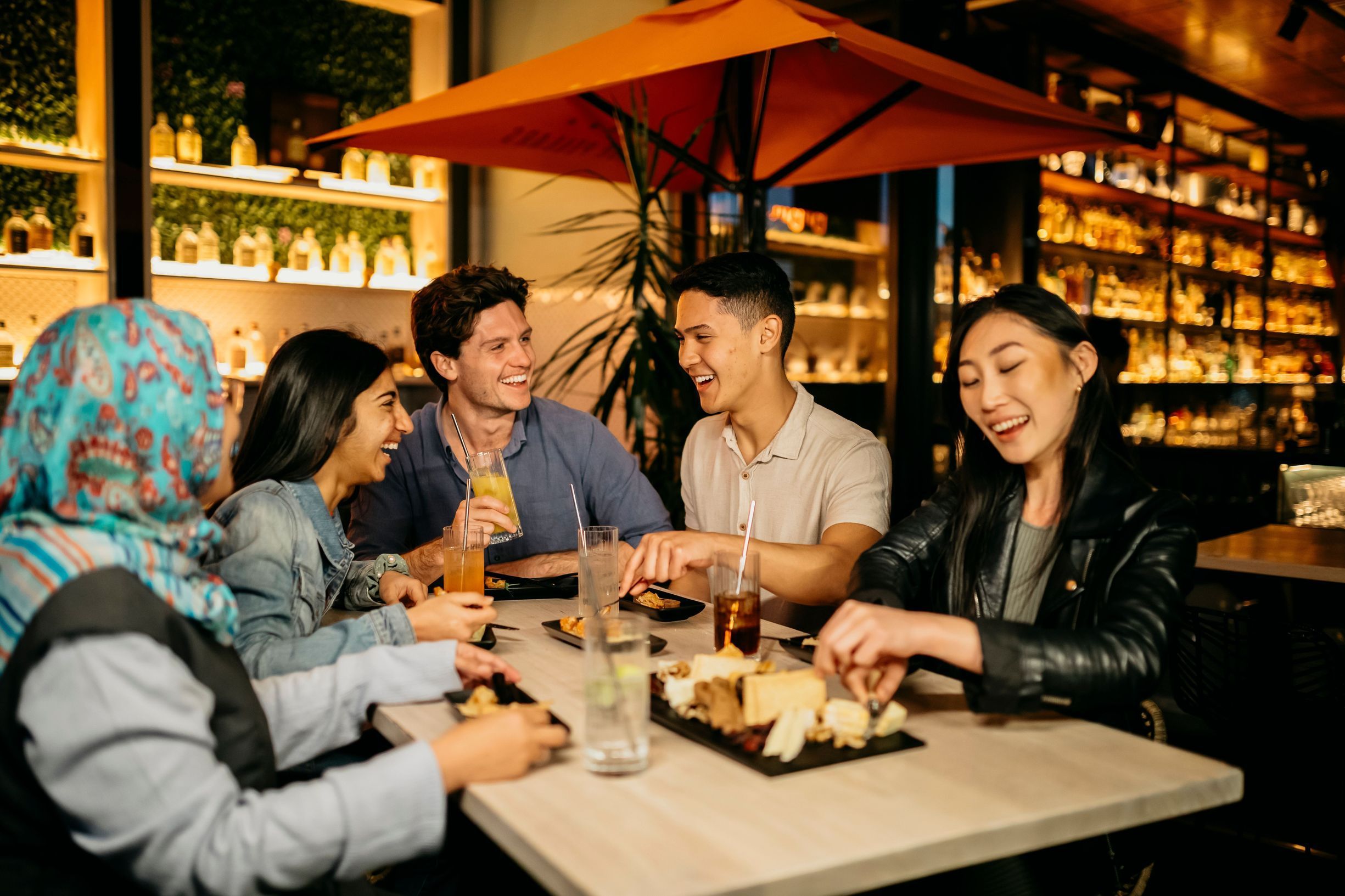 Young people enjoying drinks and food at Nick and Nora's rooftop bar.