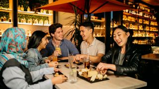 Young people enjoying drinks and food at Nick and Nora's rooftop bar.