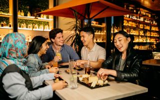 Young people enjoying drinks and food at Nick and Nora's rooftop bar.