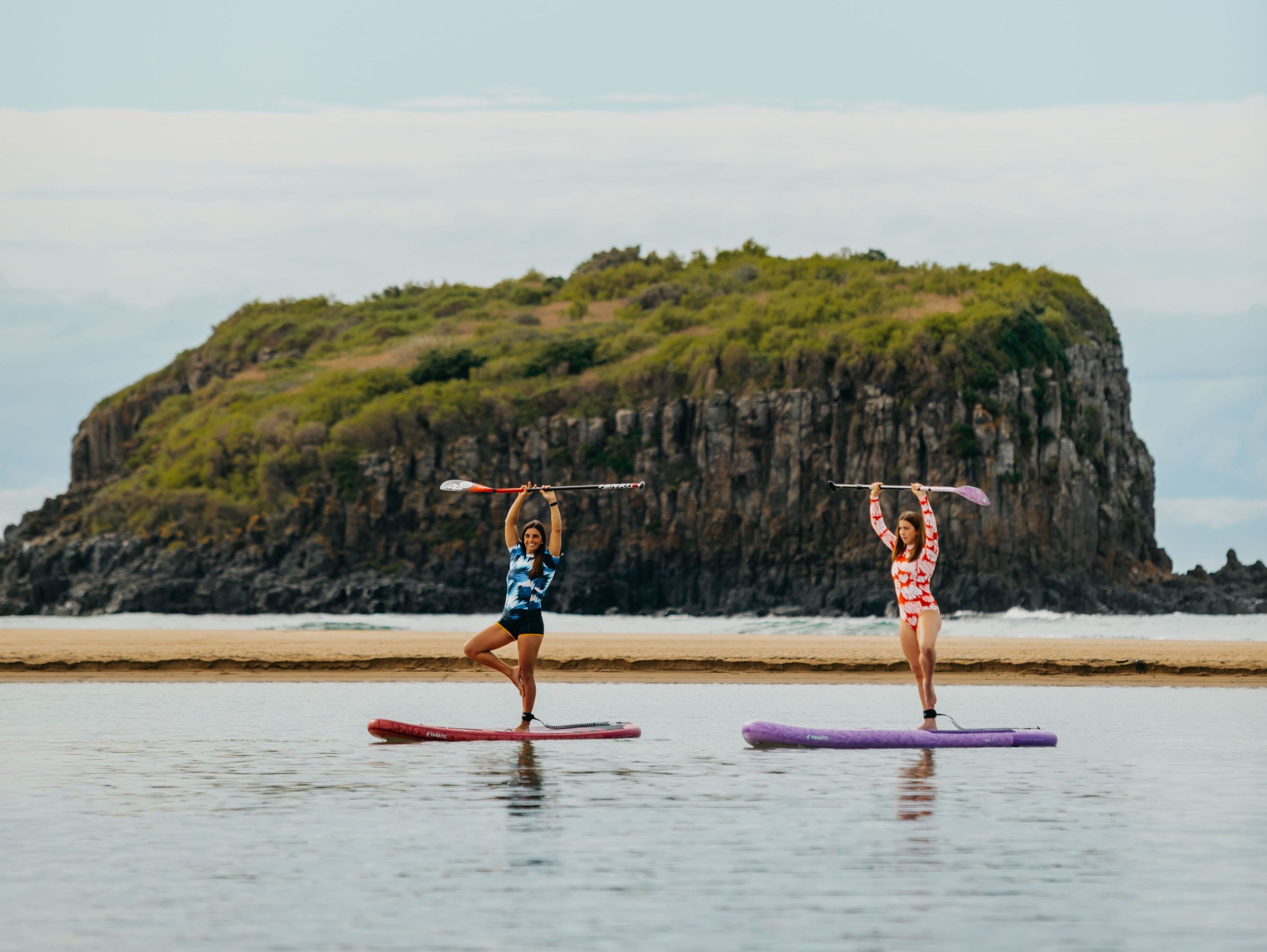 Friends enjoy stand up paddle boarding on the Minnamurra River, on the NSW South Coast