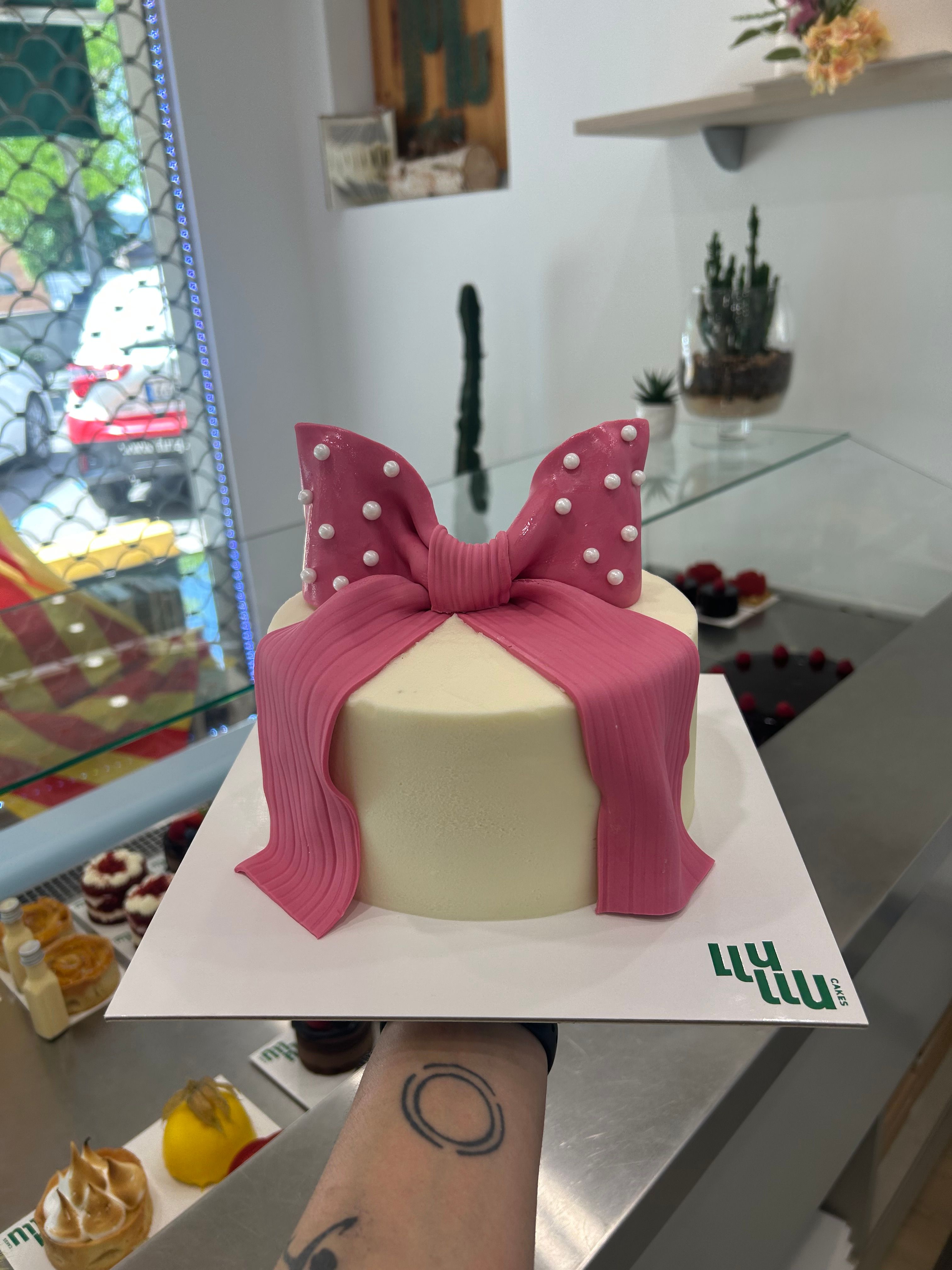 Pastel blanco lazo rosa fondant grande en el medio perlas