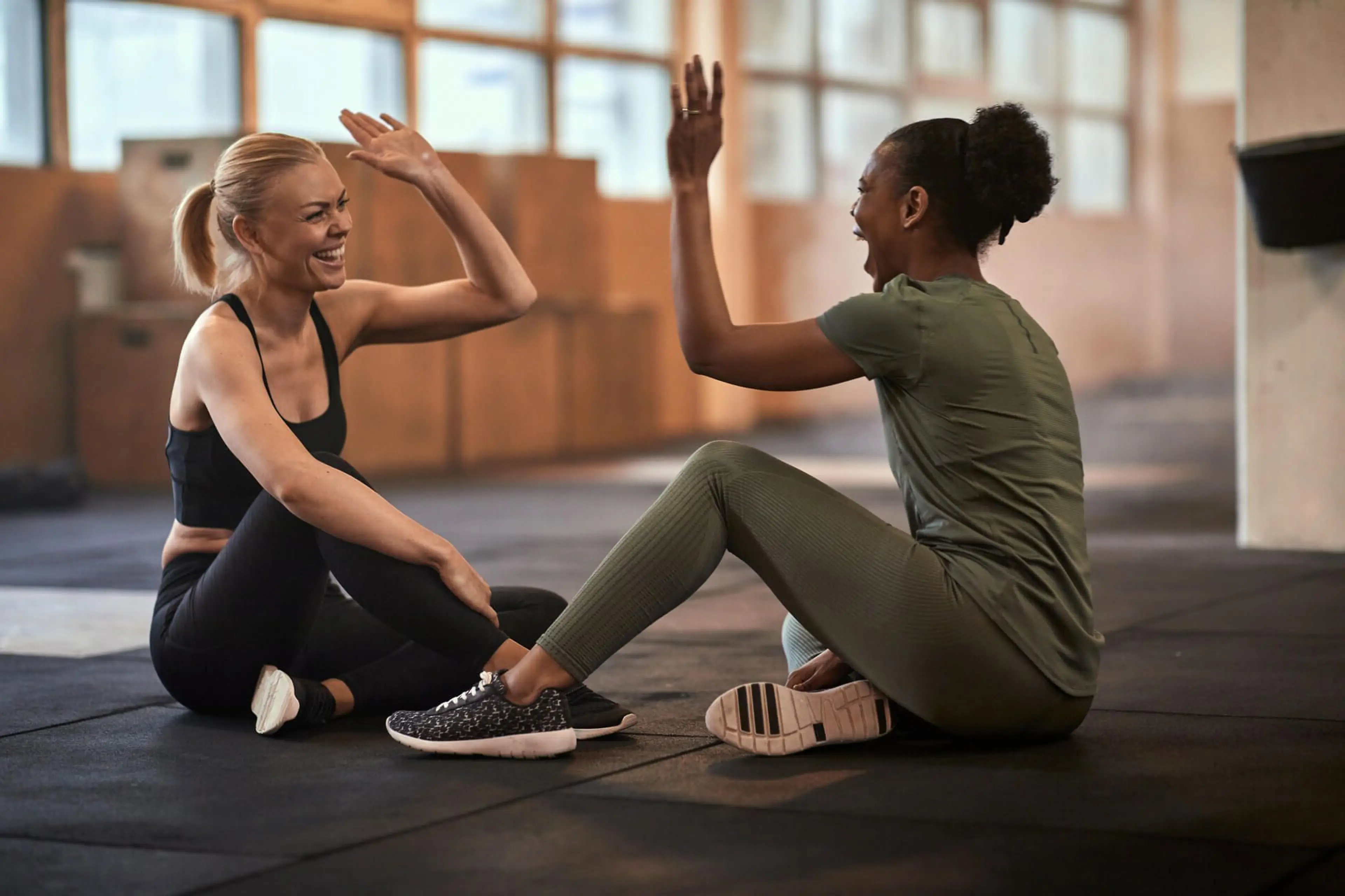 To kvinner på et treningsstudio som gir high five til hverandre