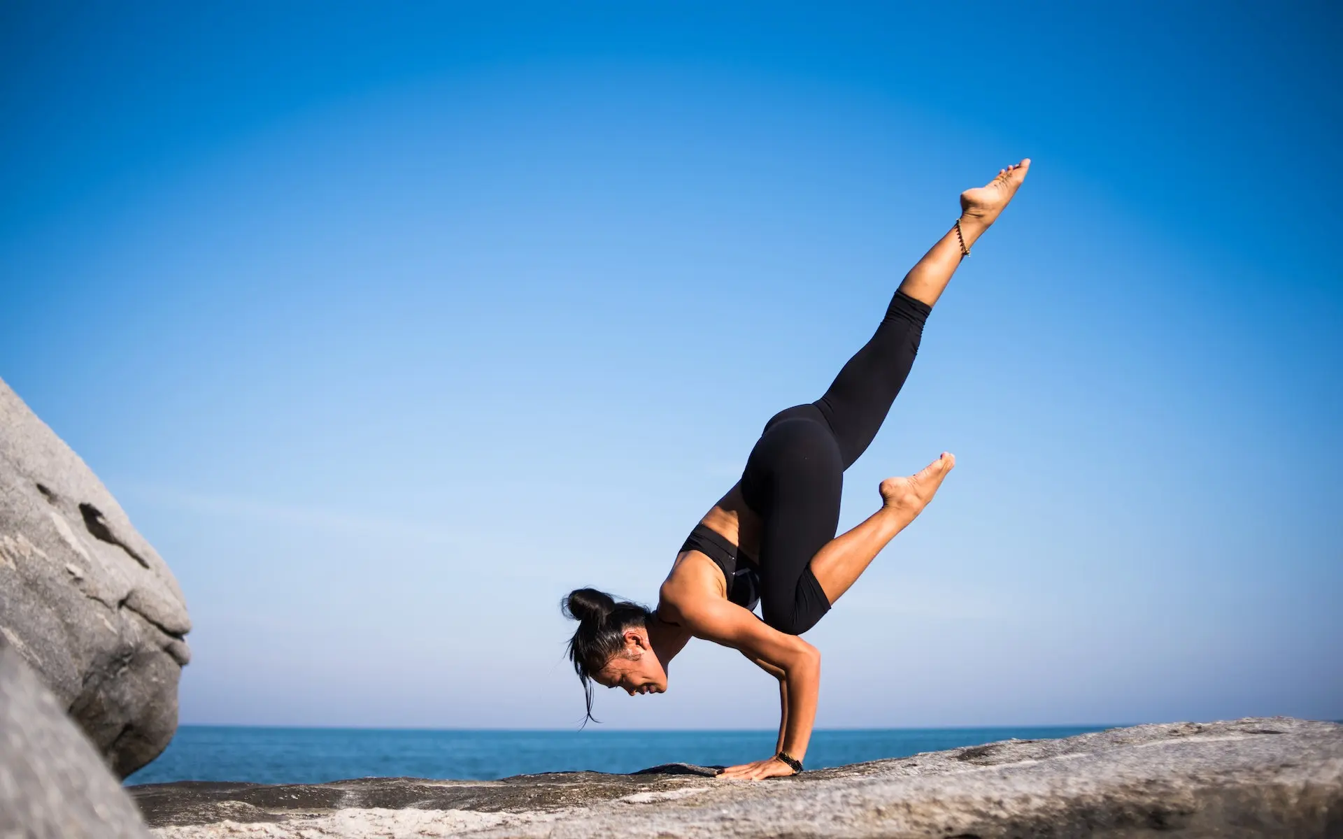 En kvinne som utfører en vanskelig yoga posisjon utendørs