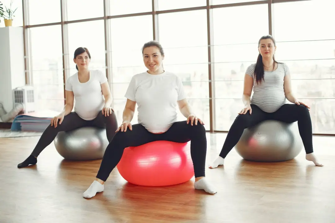 3 gravide kvinner trener på medisinball
