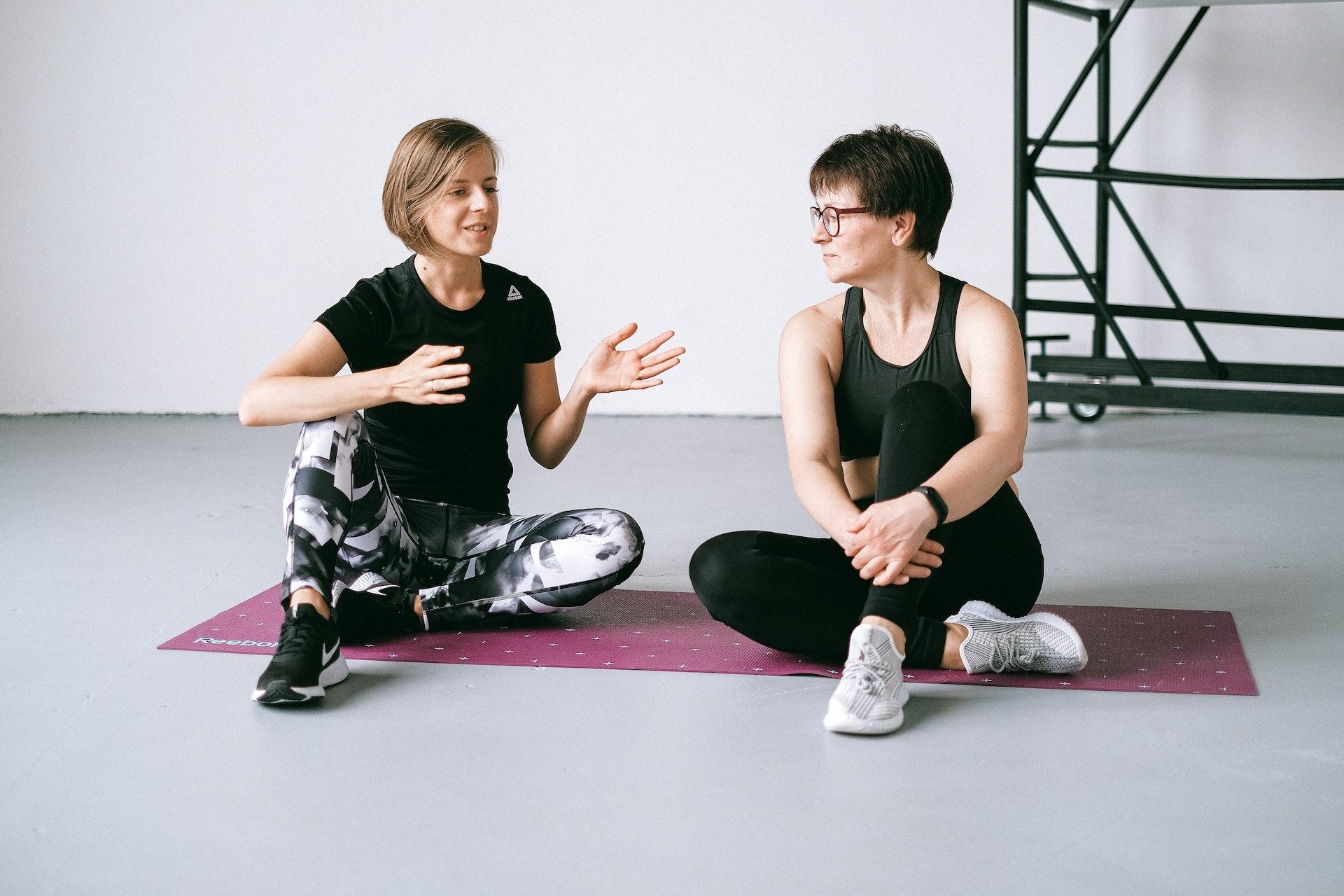 To kvinner på en treningsmatte som prater med hverandre