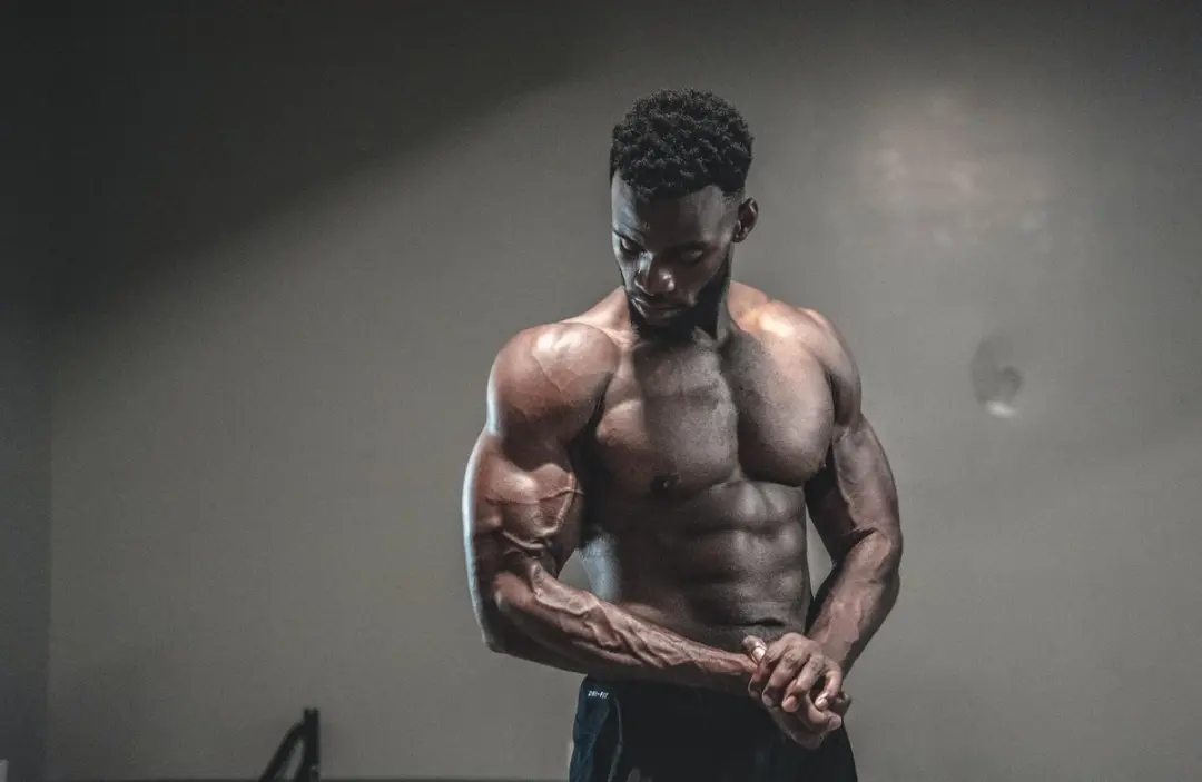 Mørk mann i bar overkropp med store muskler