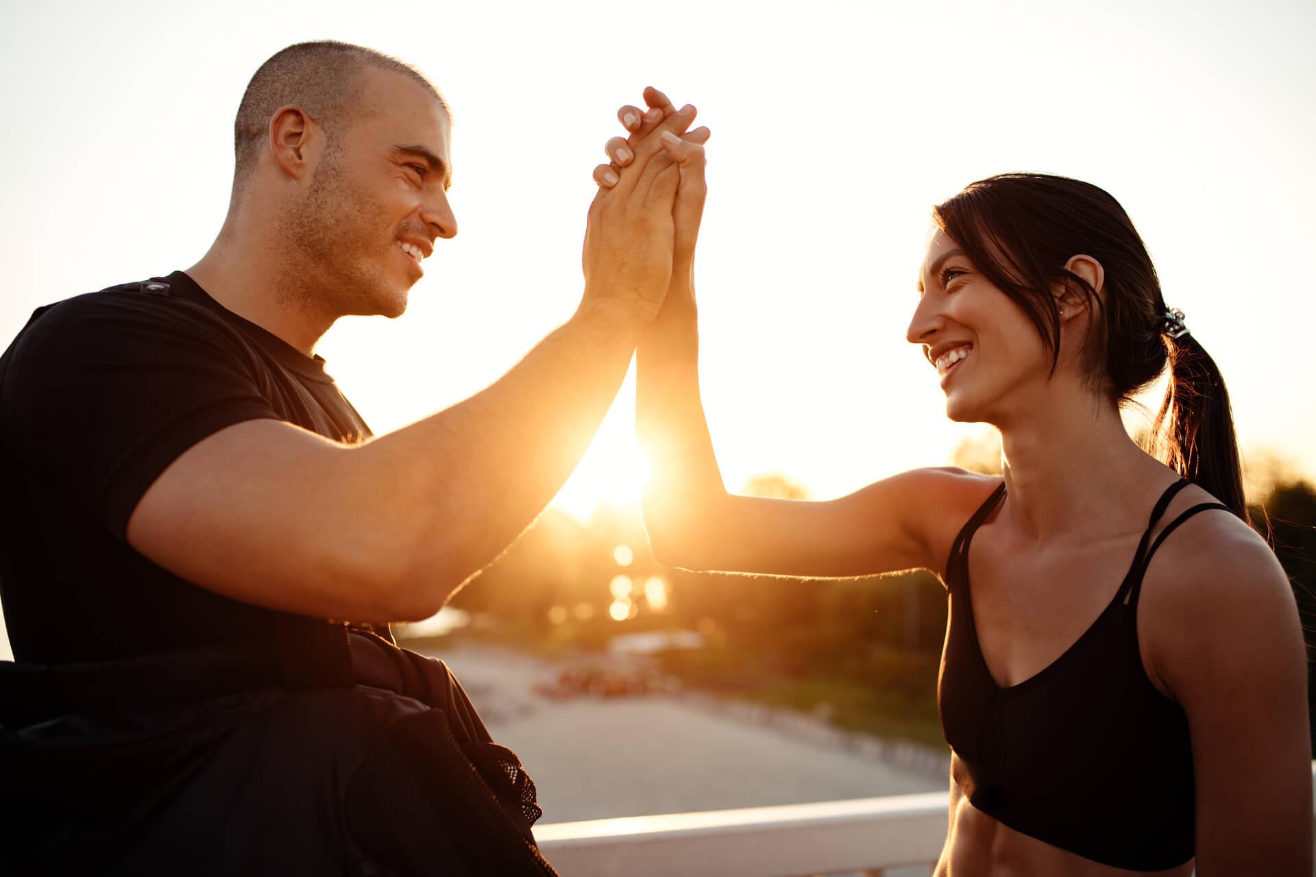 En mann og en kvinne som gir high five til hverandre under trening