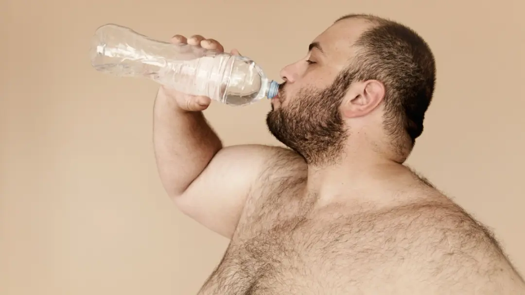 En overvektig mann drikker vann