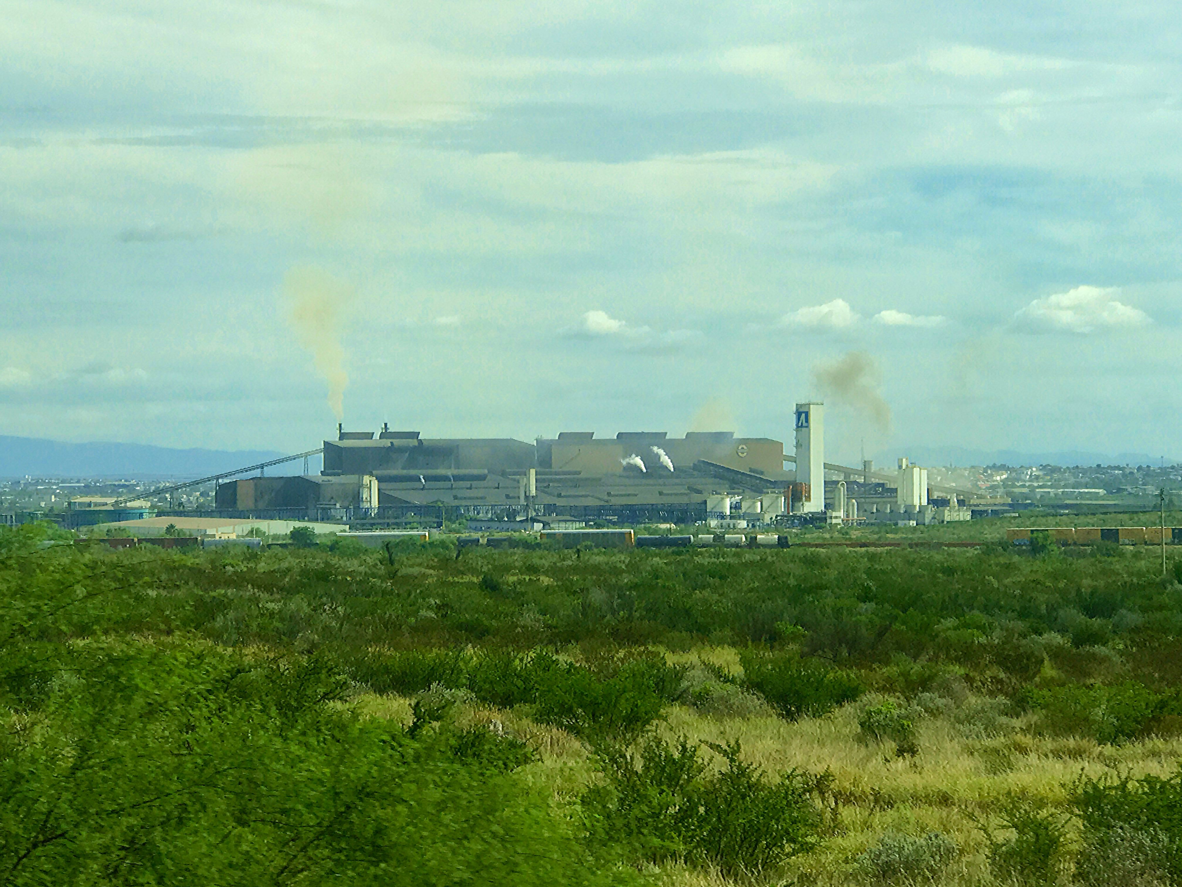 Planta siderúrgica de Altos Hornos de México en Monclova, Coahuila, con chimeneas humeantes al fondo de un llano con matorral (imagen de archivo).