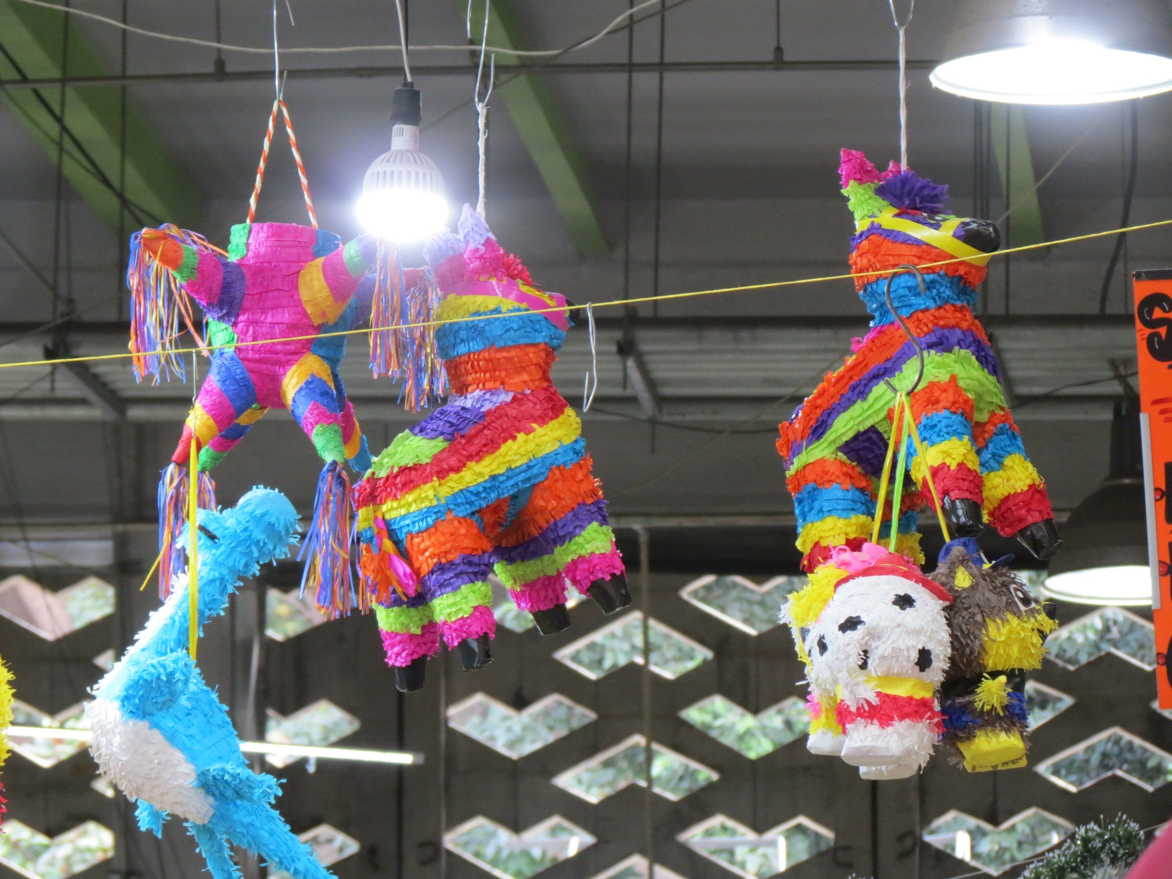 Interior del Mercado de San Juan, en la Ciudad de México, con piñatas colgadas sobre los puestos.