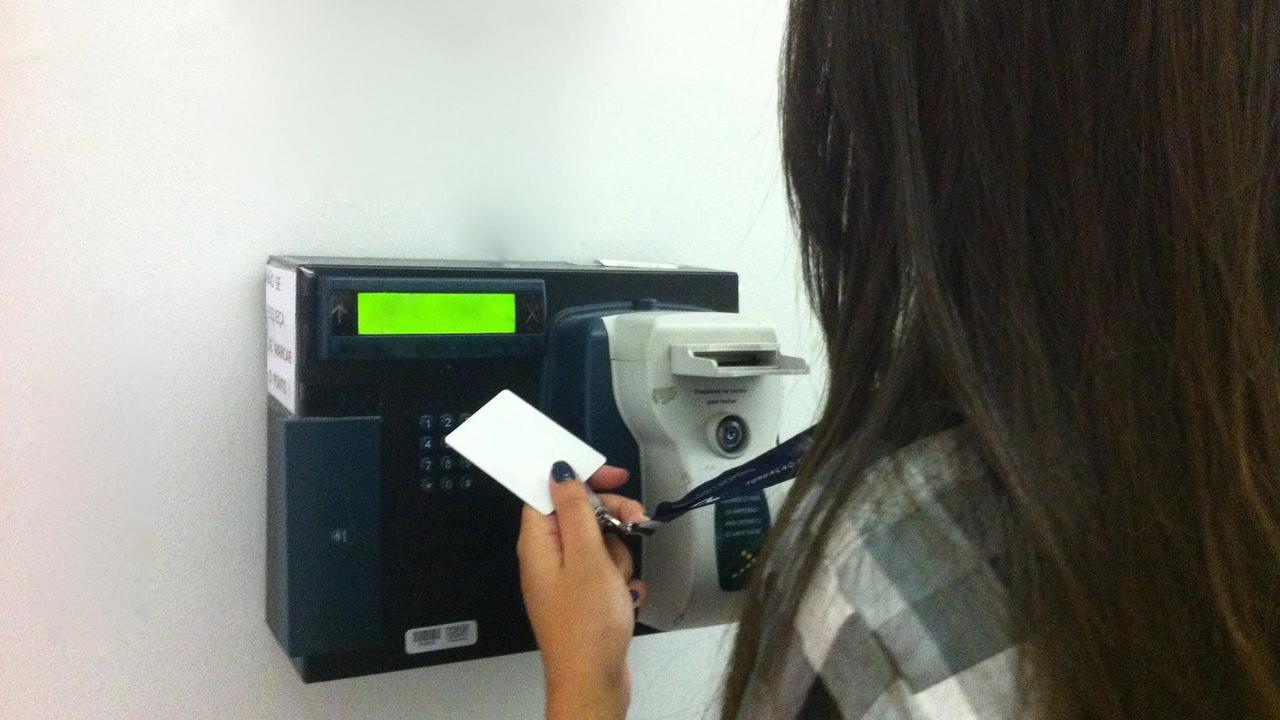 Una persona registra su entrada en un reloj checador electrónico.