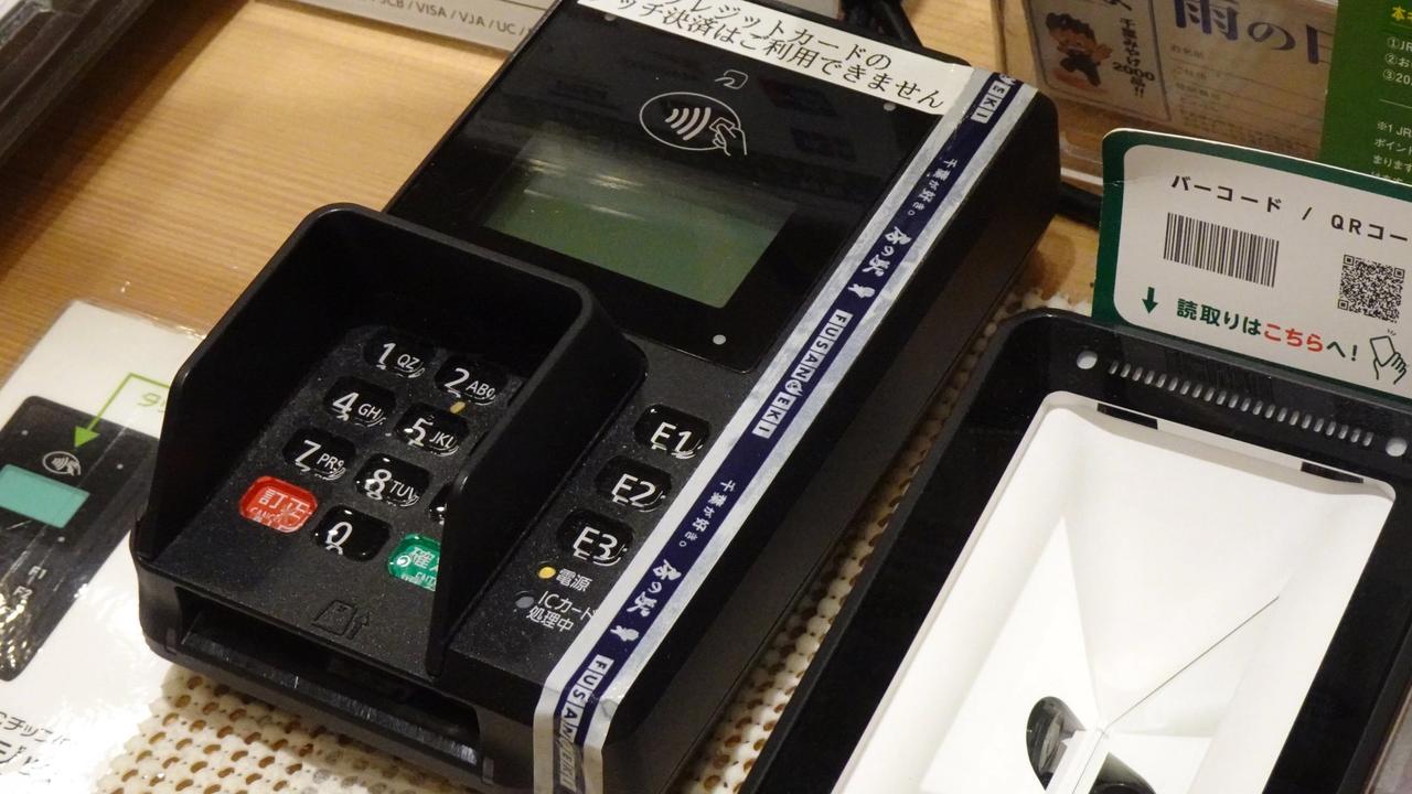 Terminal para pagar con tarjeta o por aproximación junto a un lector de códigos QR en el mostrador de un comercio (imagen de archivo, 2022).