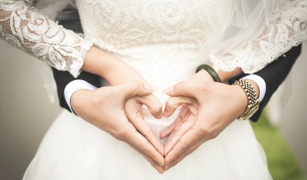 A bridal couple making a heart with their hands