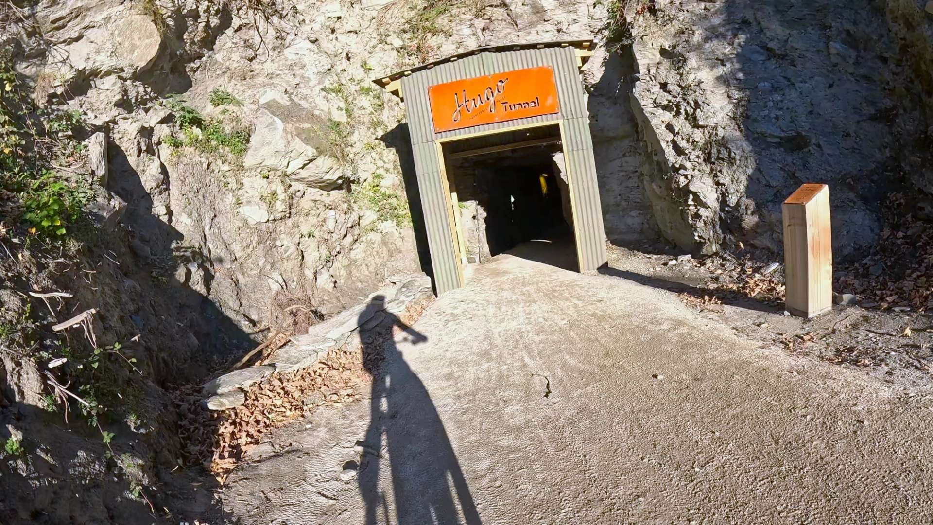 Entrance to the historic Hugo Tunnel on the Shotover River Trail, framed by rugged cliffs.