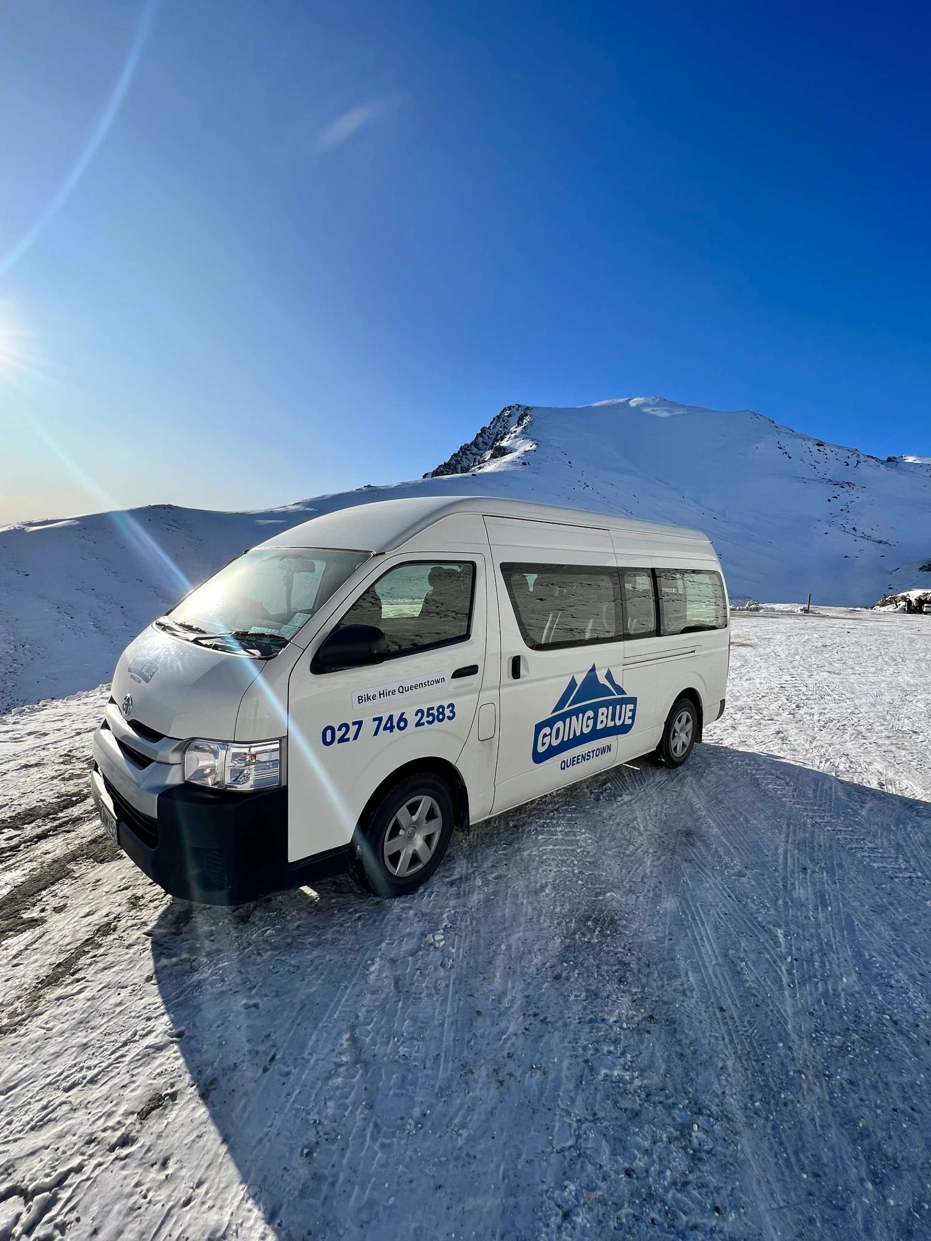 Going Blue shuttle van parked on snow at The Remarkables ski area under a clear blue sky