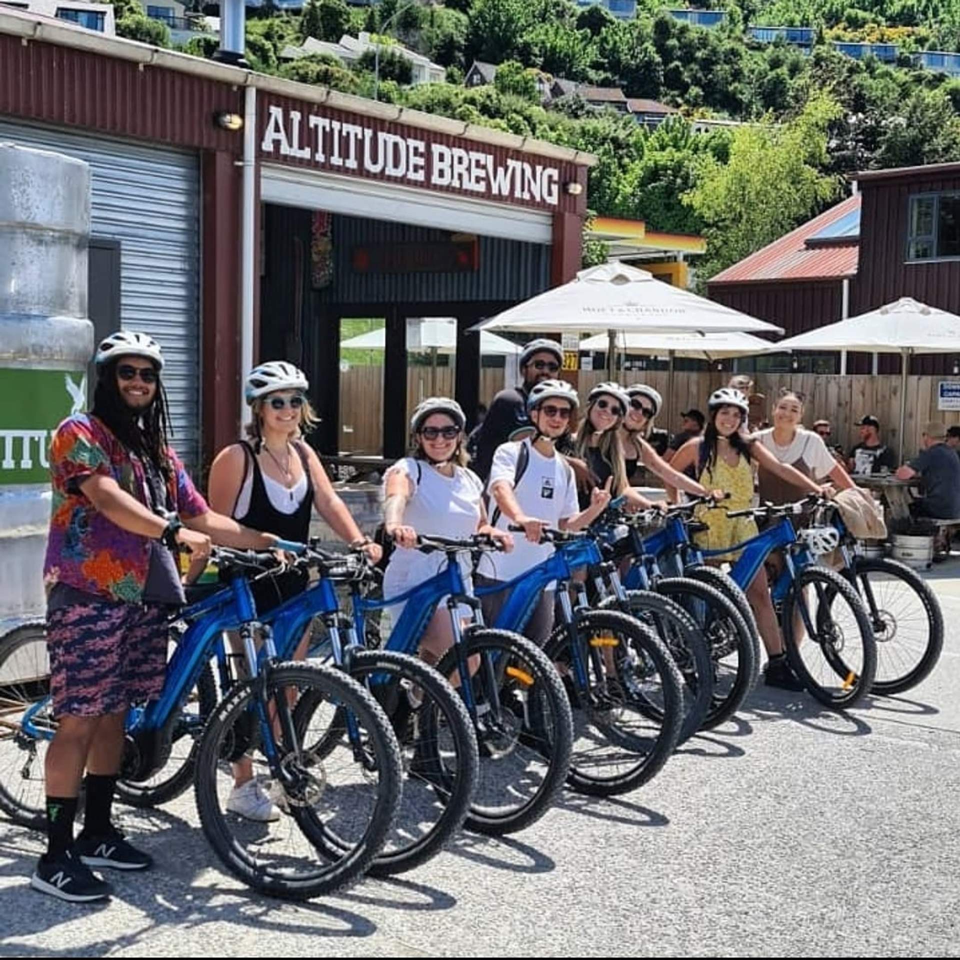Group of cyclists outside Altitude Brewery after completing the Shotover River Trail, enjoying sunshine and craft beers