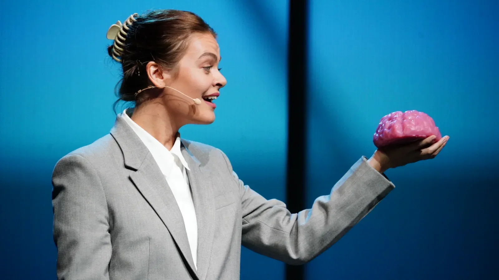 A performer holds up a model of a brain in The Effect.