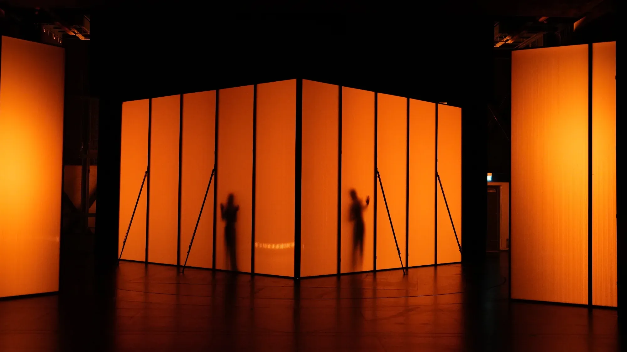 Silhouettes behind orange walls.