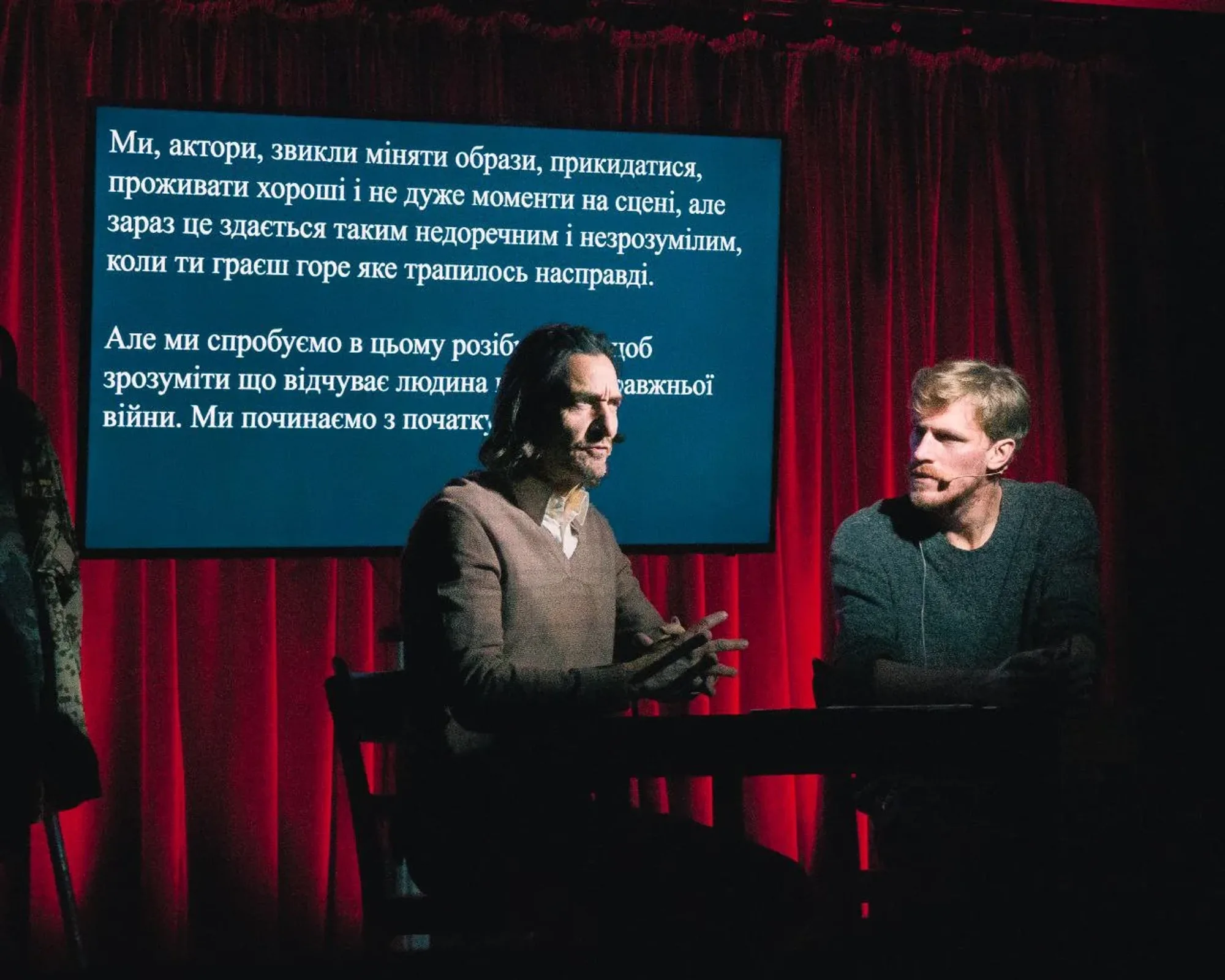The stage: two actors and a screen with projected text.
