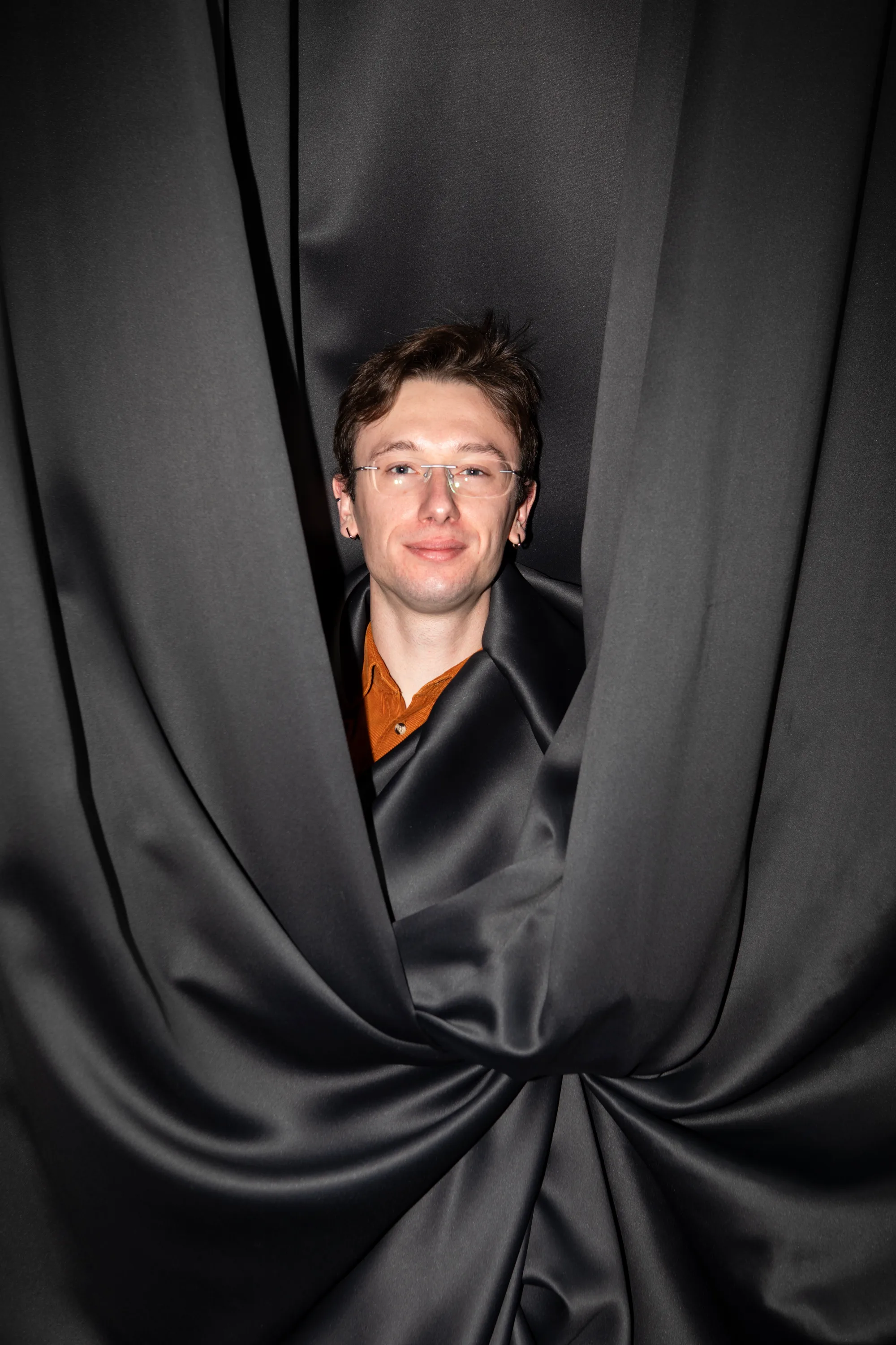 Danylo Symonovych looking out from between folds of dark fabric.